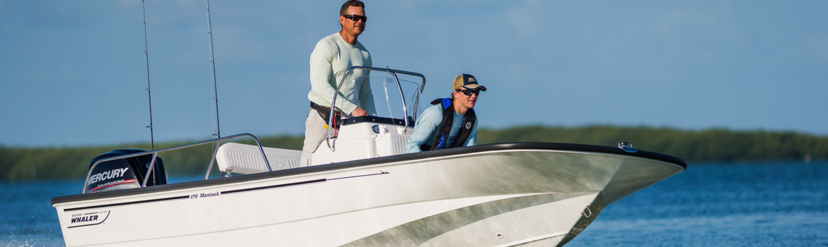 Two people on a Boston Whaler 170 Montauk boat cruising on the water on a sunny day